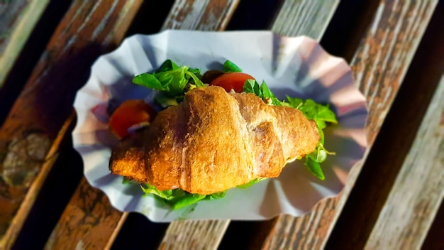 Croissant à l'avocat, tomate et herbes à l'extérieur. Nourriture végétarienne de rue.