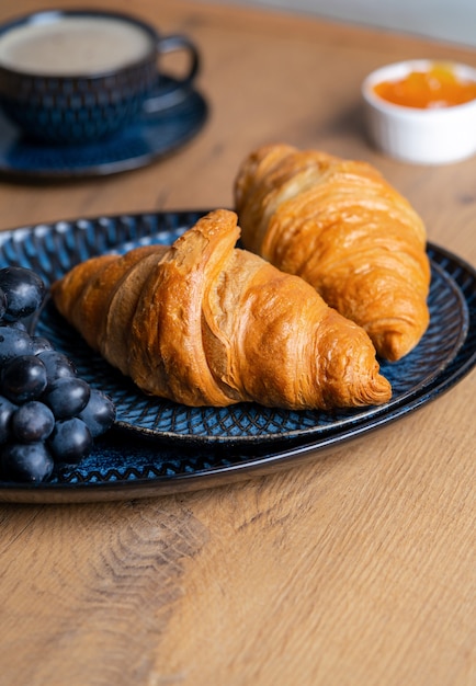 Croissant croustillant sur une assiette sur une table en bois à côté de la confiture et du jus d'orange, délicieux petit déjeuner. photo de haute qualité