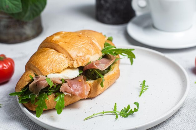 Photo un croissant avec du jambon, de la mozzarella et de la roguela sur une assiette