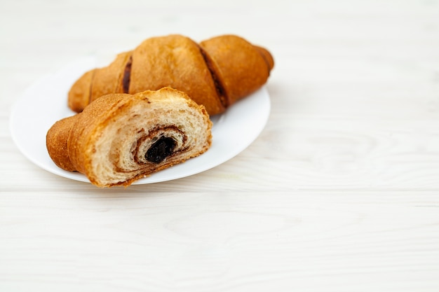 Croissant frais au chocolat sur bois blanc