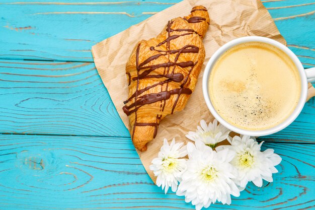 Croissant frais et café sur fond de bois