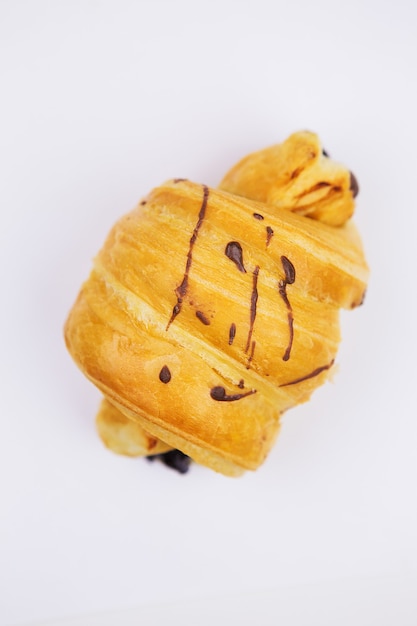 Croissant frais avec des décorations au chocolat, isolement sur fond blanc