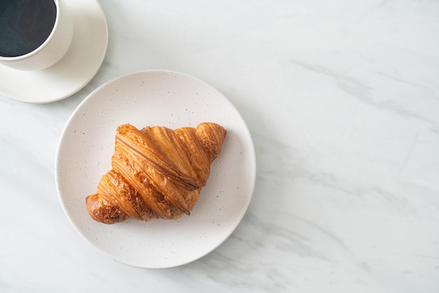 croissant frais sur plaque blanche avec café noir