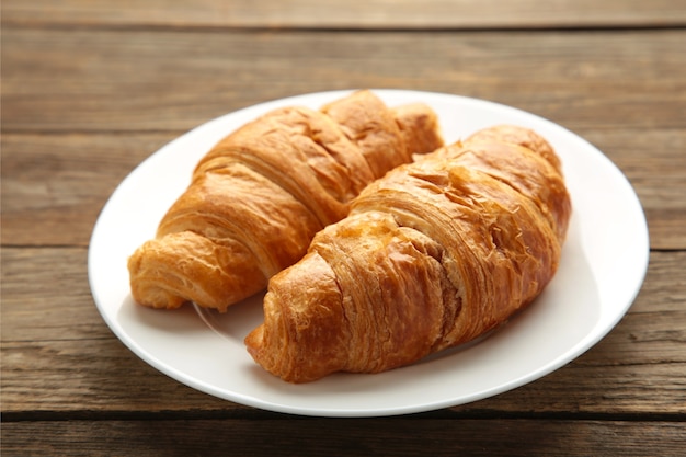 Croissant frais sur plaque sur fond de bois gris