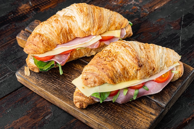 Croissant frais ou sandwich avec salade, jambon, jambon, prosciutto, sur le vieux fond de table en bois foncé