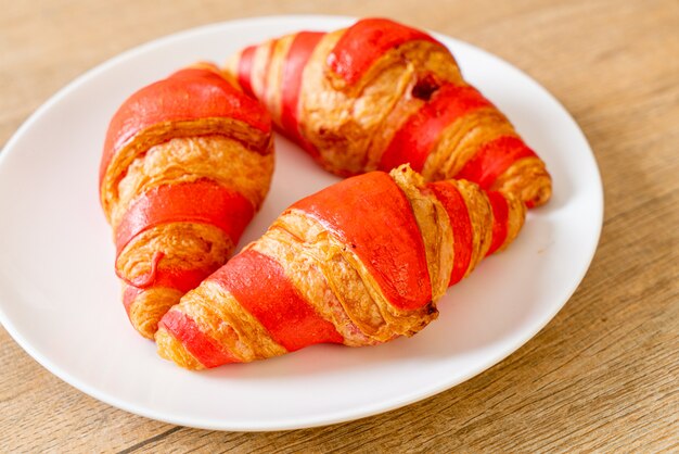 Croissant frais avec sauce à la confiture de fraises sur assiette