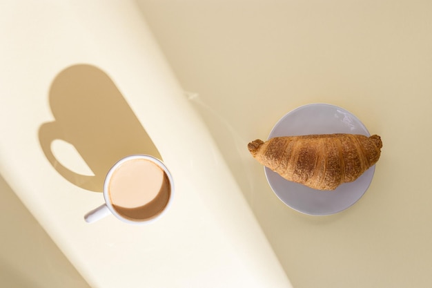 Croissant frais et tasse de café chaud avec du lait en plein soleil Petit-déjeuner le matin d'été