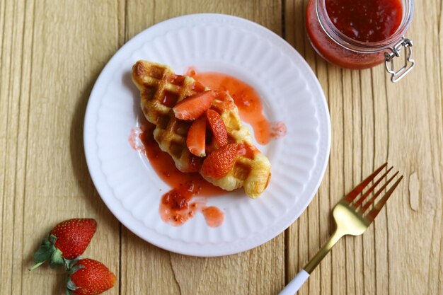 Croissant Gaufre ou croffle en assiette blanche avec compote de fraises