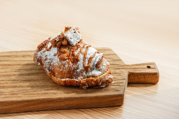 Photo un croissant avec un glaçage au chocolat est posé sur une planche à découper en bois.