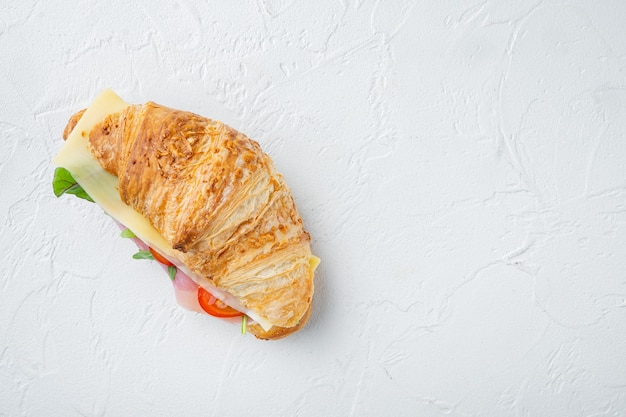 Croissant avec jambon, sur fond de pierre blanche, vue de dessus à plat, avec espace de copie pour le texte