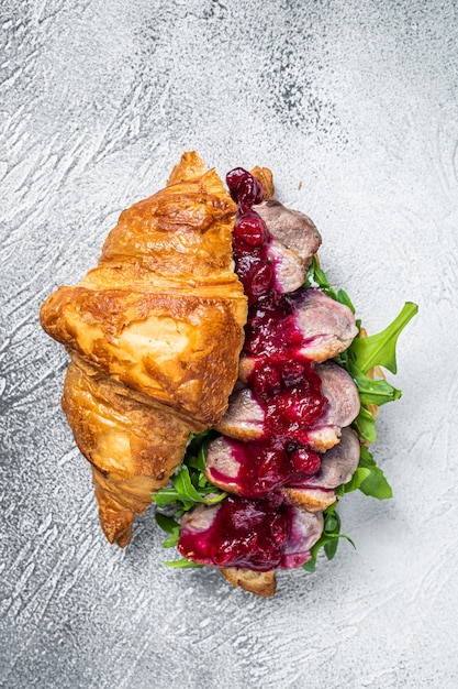 Croissant de magret de canard avec tranches de steak, roquette et sauce. table blanche. Vue de dessus.