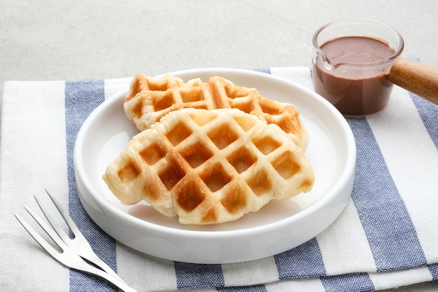 Croissant nature gaufre ou croffle avec sauce au chocolat servi dans une assiette sur fond gris