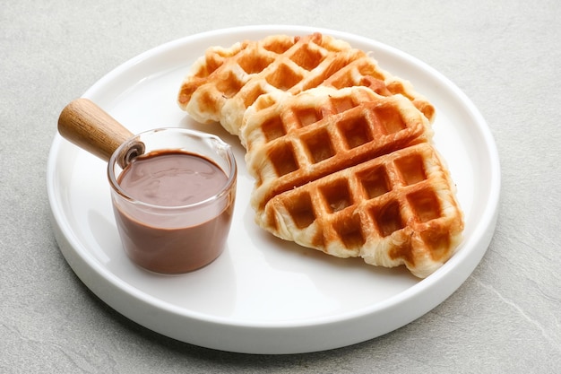 Croissant nature gaufre ou croffle avec sauce au chocolat servi dans une assiette sur fond gris