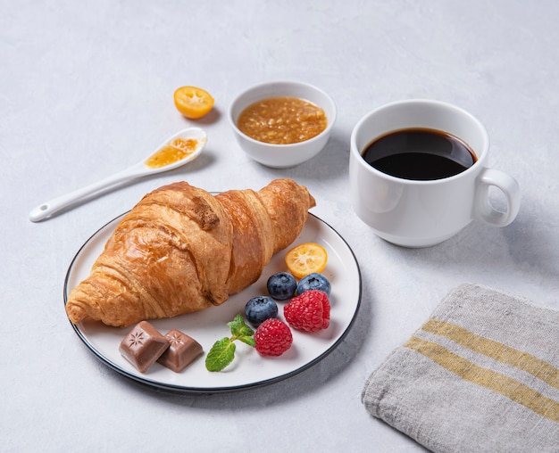 Croissant avec une tasse de café et de baies