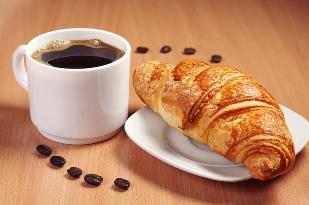 Croissant et tasse de café chaud sur table en bois