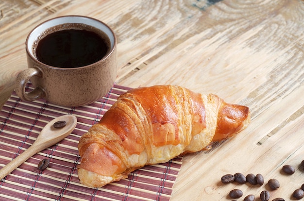 Croissant et tasse de café sur un vieux bois