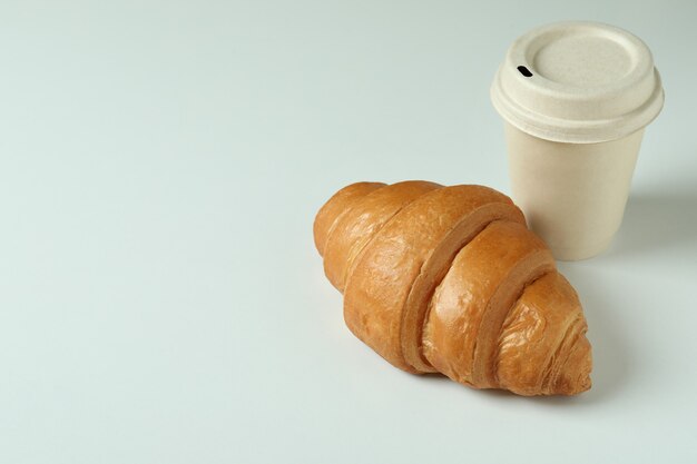 Croissant et tasse en papier sur gris clair