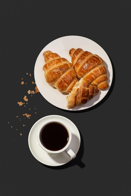 Croissants appétissants avec café sur fond noir