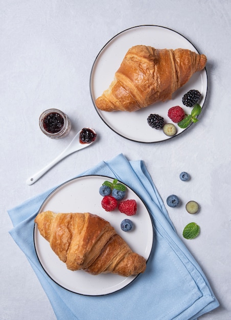 Croissants sur des assiettes avec des baies sur fond gris