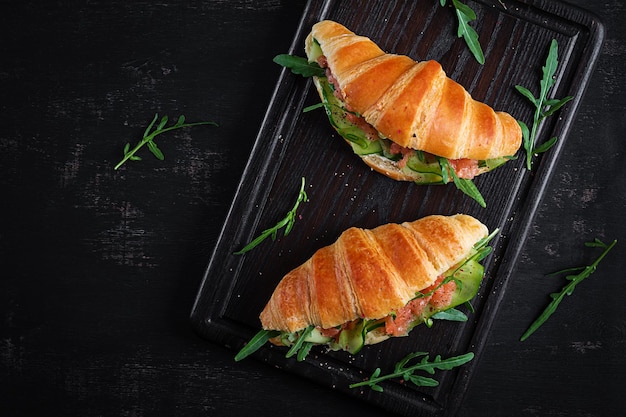 Croissants au concombre de saumon salé et roquette servis sur fond sombre Gros plan Vue de dessus