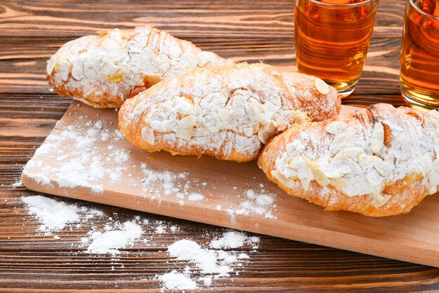 Croissants aux amandes et thé sur une table en bois.