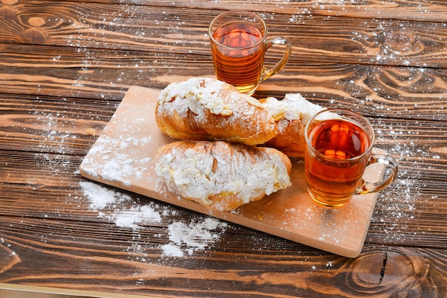 Croissants aux amandes et thé sur une table en bois