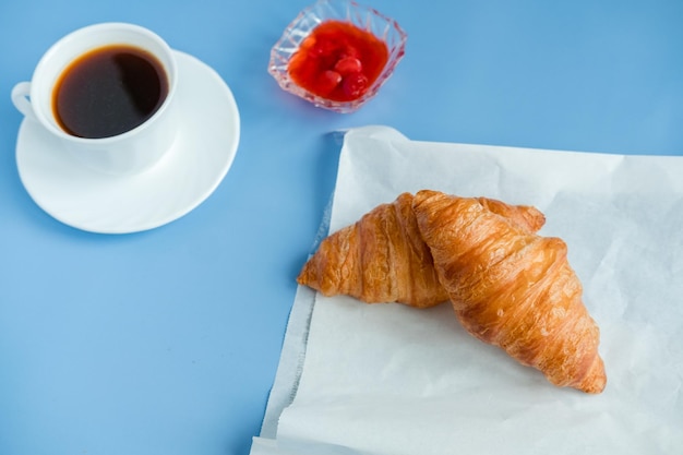 Croissants avec confiture et café du matin à plat Isolé sur fond bleu