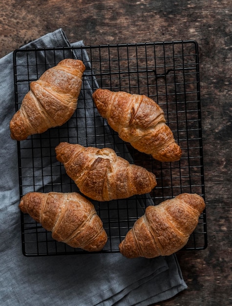 Des croissants croustillants frais sur un étagère à pain sur un fond en bois