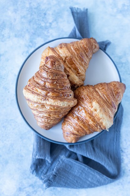 Croissants croustillants savoureux, fond de béton bleu. Boulangerie pour le petit déjeuner. Mise au point sélective.