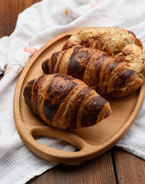 Photo les croissants cuits au four sont sur un plateau en bois. la nourriture est sur un fond brun.