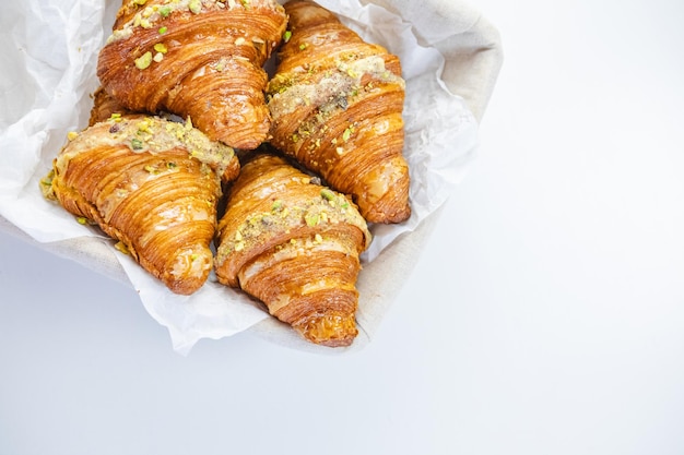 Des croissants dans un panier sur une table blanche.