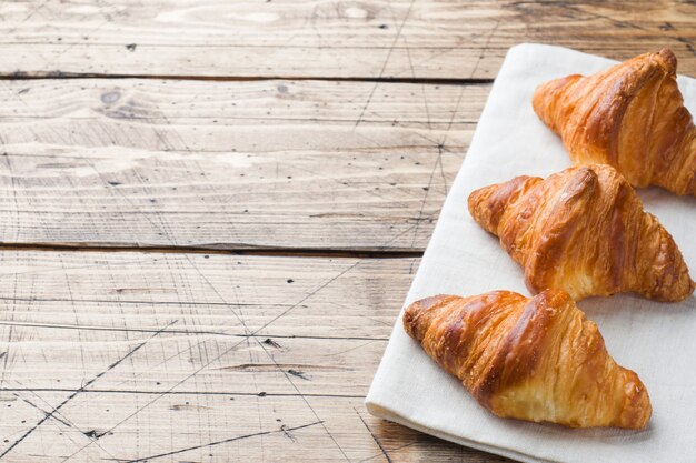 Croissants du petit déjeuner sur une assiette et une tasse de café, table en bois.