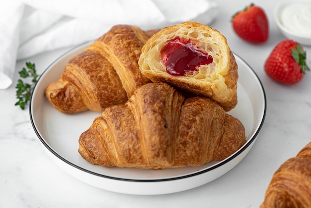 Croissants farcis à la confiture de fraises sur une assiette blanche