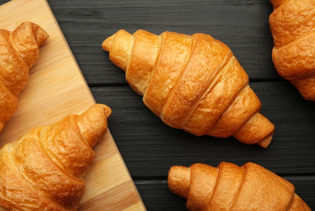 Croissants fraîchement cuits sur une planche à découper en bois sur fond noir