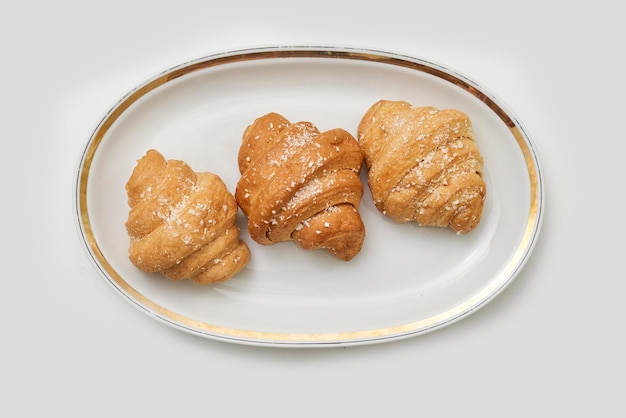 Croissants frais et appétissants sur une plaque blanche isolée sur fond blanc