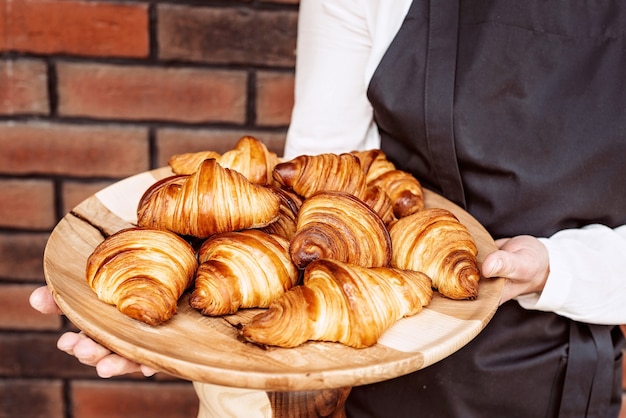 Photo croissants frais cuits au four. croissants et petits pains au beurre parfumé chaud sur un support en bois