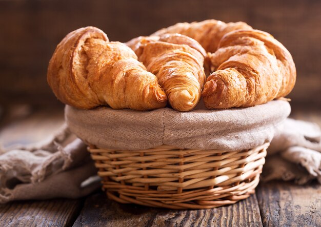 Croissants frais dans un panier sur une table en bois