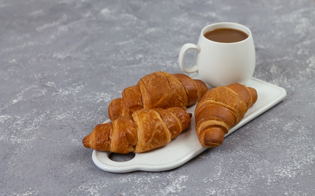 Croissants français fraîchement cuits et tasse de café sur une table en pierre rustique