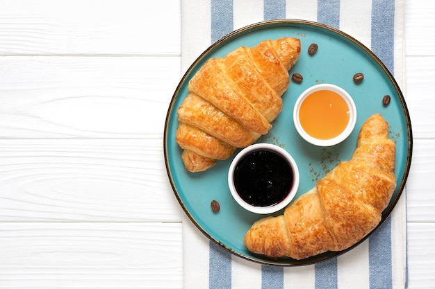 Croissants français frais avec confiture de myrtilles, miel et tasse de café