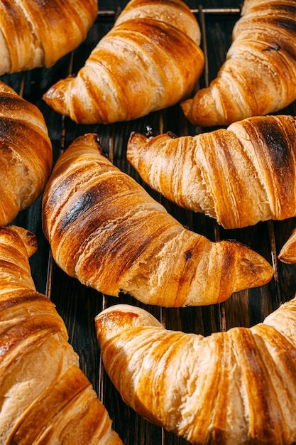 Croissants sur une grille de cuisson cool après cuisson sur une table en bois sombre