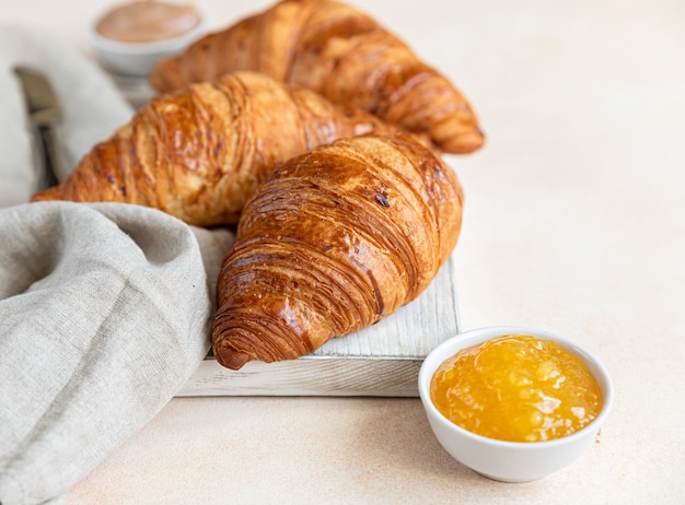 Croissants sur planche à découper en bois avec de la confiture et de la crème au chocolat