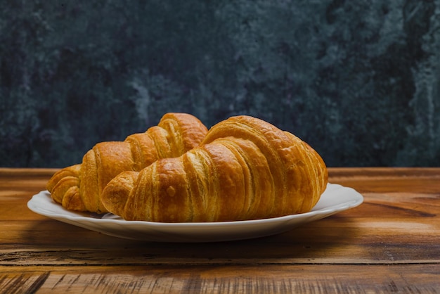 Croissants en plaque blanche sur table en bois Vue latérale