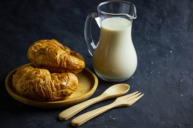 Croissants Sur Un Plat En Bois Et Pot à Lait Sur La Table