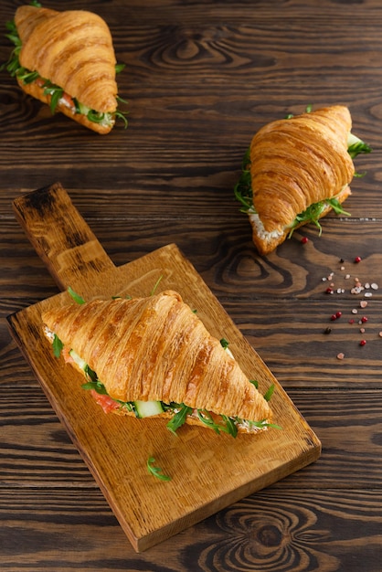 Croissants sandwichs au fromage à la crème de concombre saumon et roquette sur une table en bois