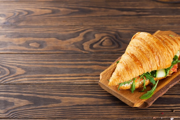 Croissants sandwichs au fromage à la crème de saumon et roquette sur planche de bois Espace de copie