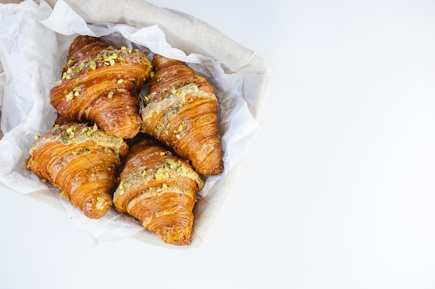 Croissants se reposant dans un panier en osier rustique au sommet d'une table blanche propre