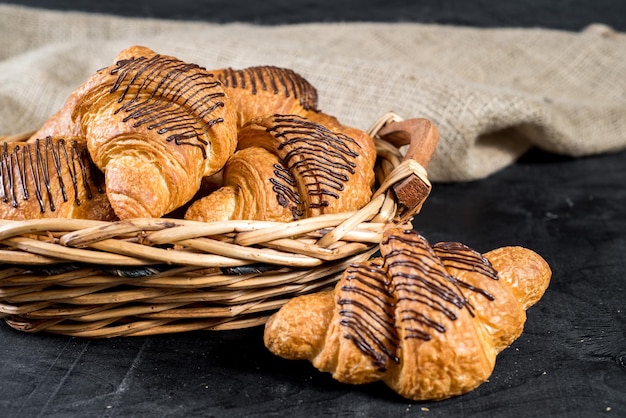 Croissants sucrés dans le panier sur fond noir