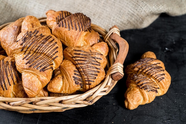 Croissants sucrés dans le panier sur fond noir