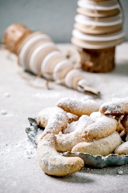 Croissants de vanille biscuits de Noël traditionnels faits maison avec du sucre glace. Sur plaque en céramique avec des décorations de Noël en bois sur une surface gris clair.