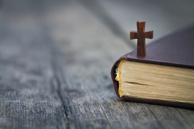 Croix et Bible sur fond de bois.